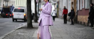 Девушка в лиловом костюме стоит на улице