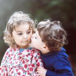 Мальчик целует девочку в щеку